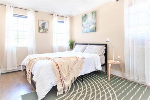a bedroom with a bed with white sheets and windows at Tonel Paradise in Rosedale