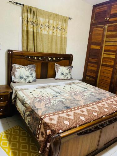 een slaapkamer met een bed met een houten hoofdeinde bij TerraNova IMMO in Mbour