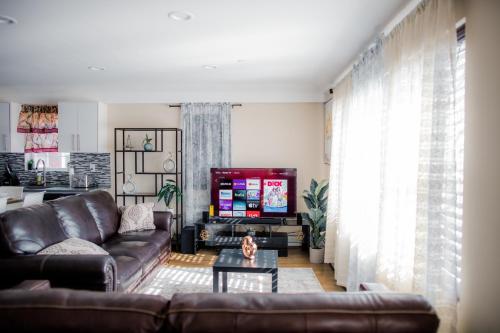 a living room with a couch and a tv at Tonel Paradise 1BR private entrance Near JFK in Rosedale
