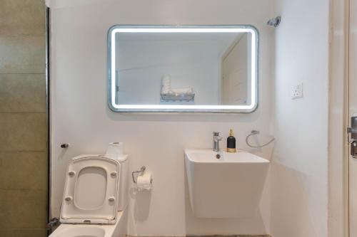 a bathroom with a toilet and a sink and a mirror at Aima Apartments in Lekki