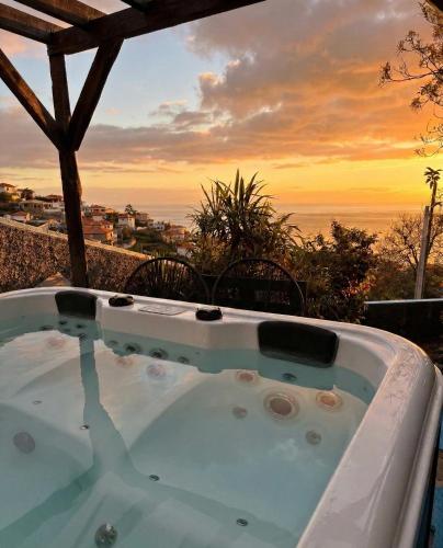 a hot tub with a sunset in the background at Granny House Madeira in Funchal