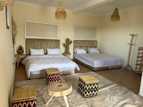 a bedroom with two beds and a table and chairs at Be Nomad Agafay Camp in El Karia
