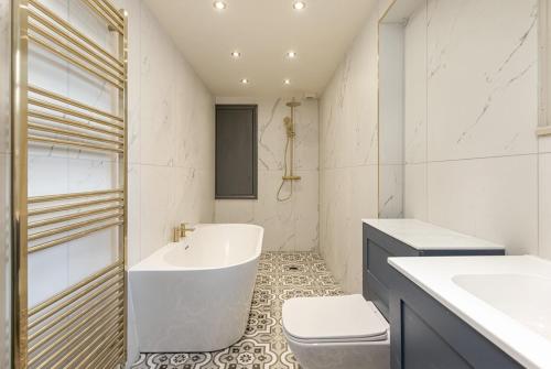 a bathroom with a tub and a toilet and a sink at The Victorian Suite in Marske