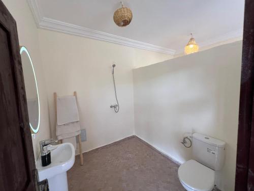 a white bathroom with a toilet and a sink at Be Nomad Agafay Camp in El Karia