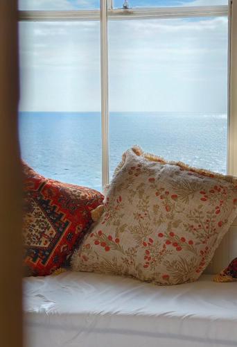 a window with pillows on a bed next to the ocean at Ocean Whisper - 2 Bedroom Sea Front Apartment in Folkestone