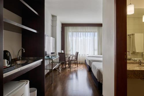 a hotel room with two beds and a desk at Mercure Belo Horizonte Lourdes in Belo Horizonte