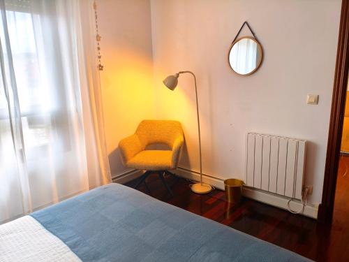 a bedroom with a yellow chair and a lamp at Don Divino in Medina de Pomar