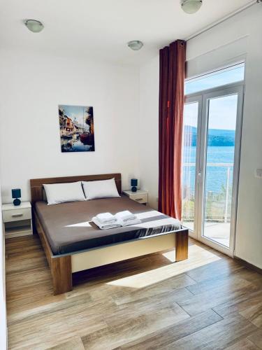 a bedroom with a bed and a large window at SF Apartments Lux in Dobra Voda