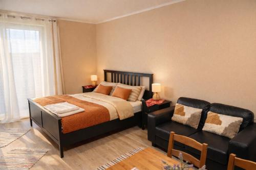 a bedroom with a bed and a leather couch at Apartment Riviera 13 Lipno in Lipno nad Vltavou