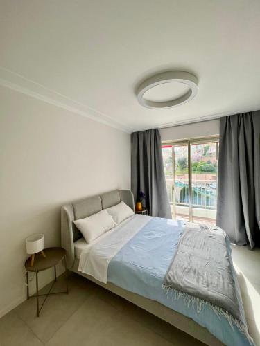 a bedroom with a bed and a large window at Sea View Apartment - Residence Les Sablettes in Menton
