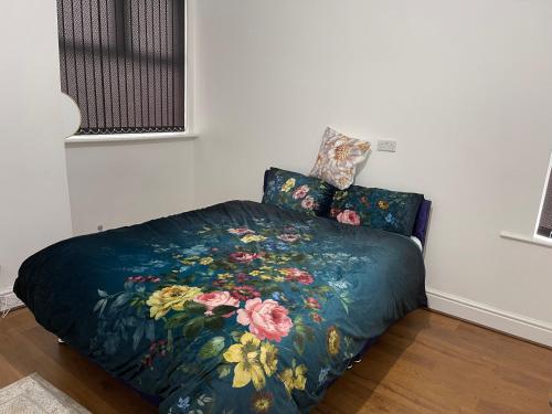 a bed with a blue comforter with flowers on it at Princess shahzadi in Manchester