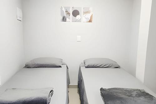 two beds in a room with white walls at Studio IX - Com Ar Condicionado - Jundiaí in Jundiaí