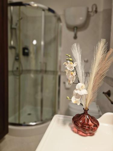 a vase with white flowers on a table in a bathroom at Due Passi dal Gate in Salerno Airport - Aeroporto di Salerno