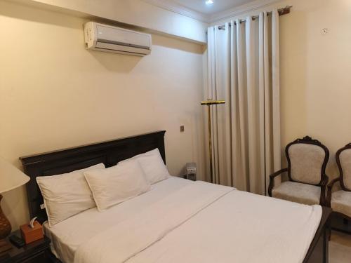 a bedroom with a white bed and a chair at The Aristocrat Manor in Islamabad