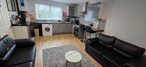 a living room with black leather furniture and a kitchen at Reardon near warwick hospital, free parking, fast wifi, sleeps 5 in Warwick