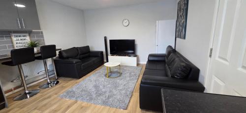 a living room with a black leather couch and a table at Reardon near warwick hospital, free parking, fast wifi, sleeps 5 in Warwick