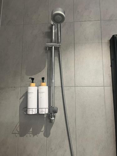 a shower with two white bottles on a shelf at Nordic NOVA Studio in Stockholm