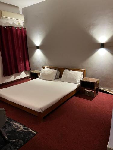a bed with white sheets and pillows in a room at Durrani Lodges - Islamabad G11 in Islamabad