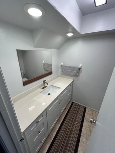 a white bathroom with a sink and a mirror at Plum Cozy Spot in Seffner