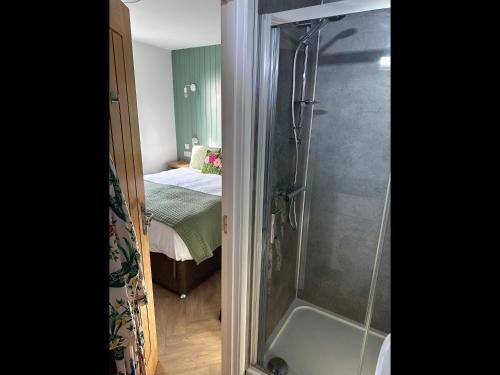 a bathroom with a shower and a bedroom with a bed at Garden House Rooms in Kirkwall