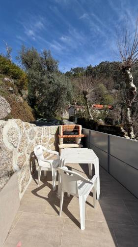 a patio with two white chairs and a table at Gerês Natura in Valdosende