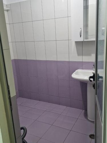 a bathroom with a sink and purple and white tiles at Elegant Apartment City Center in Fier