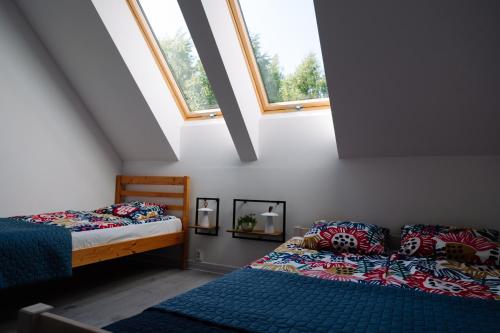 a attic bedroom with two beds and two windows at 4 Pory Roku in Darłowo