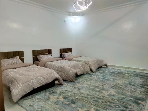 three beds are lined up in a room with a rug at شقق العون in Jerash