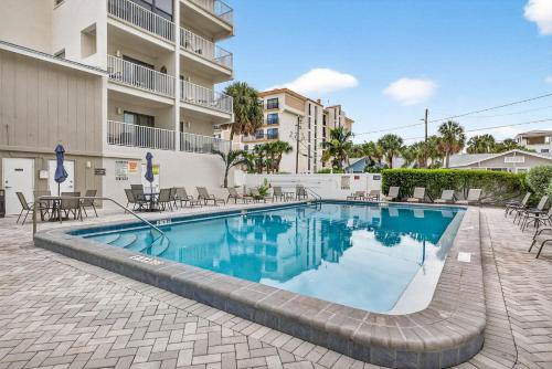 a swimming pool with tables and chairs next to a building at 5 Star 30 Steps from Beach l 3m Walk to Rest & Shops in Clearwater Beach