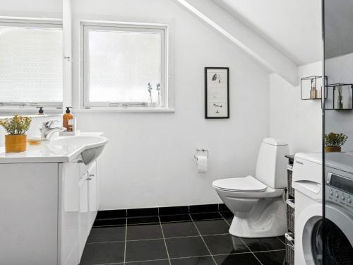 a white bathroom with a sink and a toilet at Bright Cottage with Hot Tub in Ebeltoft