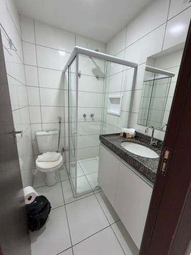 a bathroom with a toilet and a glass shower at Flat Vila Monte Castelo in Gravatá
