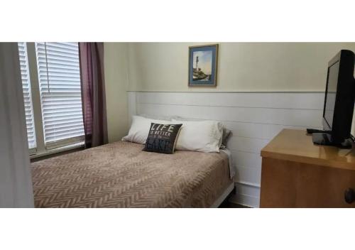 a small bedroom with a bed and a television at #7 Kipling Cottages Last Resort on Lake Michigan in Gladstone
