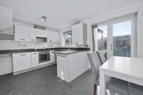 a kitchen with white cabinets and a table and a window at Golf Let in Southport