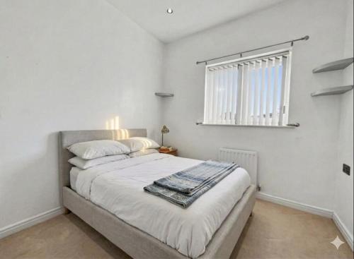 a bedroom with a large bed with white walls and a window at Golf Let in Southport