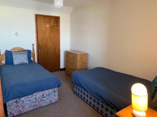a bedroom with two beds and a table with a lamp at Azure Lodge in Bundoran