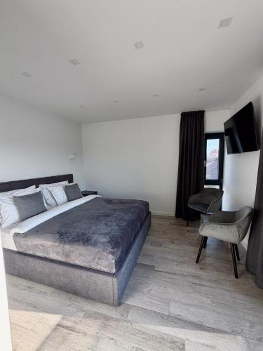 ein Schlafzimmer mit einem großen Bett und einem Stuhl in der Unterkunft ASPECT House in Caransebeş