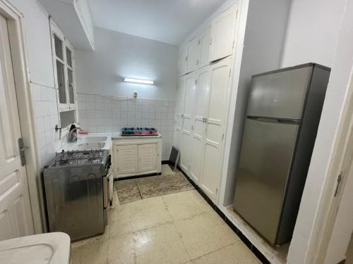 a kitchen with a stainless steel refrigerator and white cabinets at Maison Fatima in Mahdia
