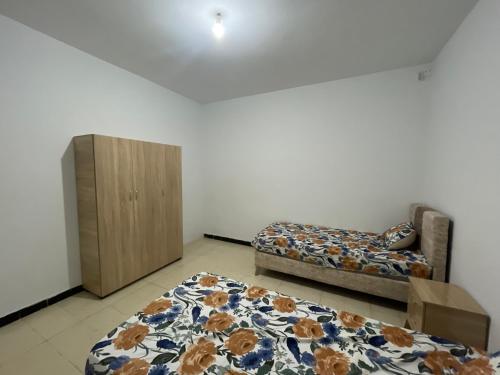 a living room with two beds and a cabinet at Maison Fatima in Mahdia