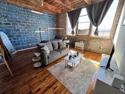 a living room with a couch and a brick wall at 420 Friendly Industrial Loft Near Downtown Detroit in Detroit