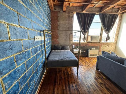 a room with a bed against a brick wall at 420 Friendly Industrial Loft Near Downtown Detroit in Detroit