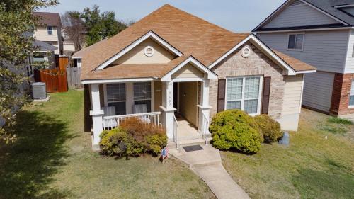 a house with a porch and a woman standing in the yard at Modern Updates - Great Location - King Bed- BMT in San Antonio