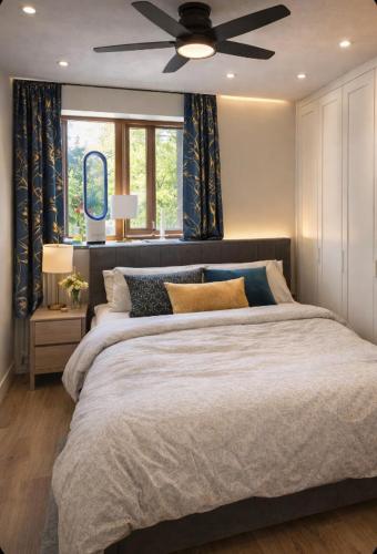 a bedroom with a large bed with a ceiling fan at Read Oak Lodge - Spring Offer - Free Parking - Kitchen Laundry Facility - Near PRUH - Orpington - 20 Mins from London Bridge in Farnborough