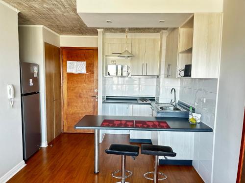 a kitchen with a counter and two stools in it at Apartamento Vista Buena in Talca
