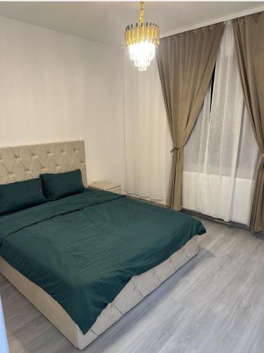 a bedroom with a green bed with a chandelier at Atlantis Suites Bragadiru Bucuresti Parcare gratuita Self checkin in Bragadiru