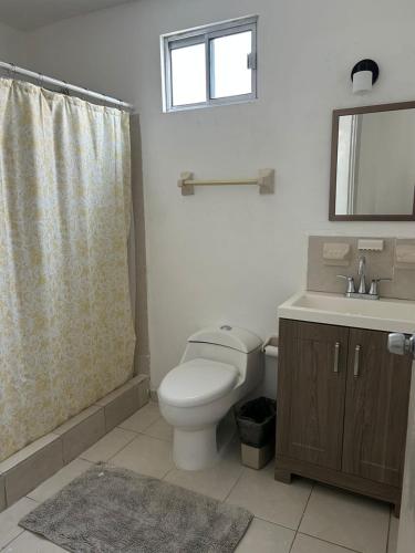 a bathroom with a toilet and a sink and a mirror at Casa Antonio in Reynosa