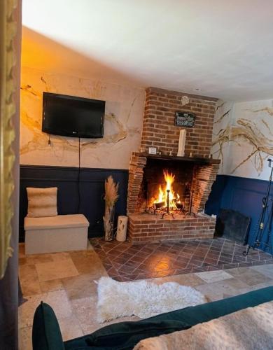 a living room with a fireplace and a tv at Loft Spa Prestige in Villampuy
