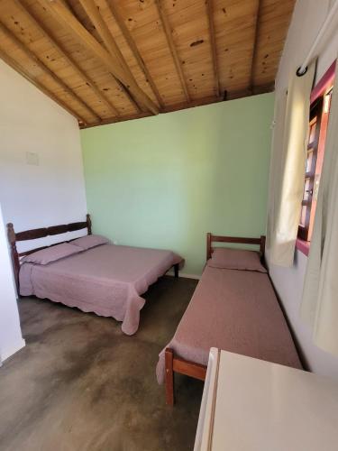 two beds are in a room with a wooden ceiling at Casa Encantada in Sêrro