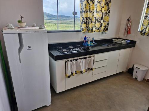 a white kitchen with a stove and a sink at Casa Encantada in Sêrro