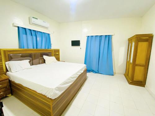 a bedroom with a large bed with blue curtains at Sanga City in Bakel