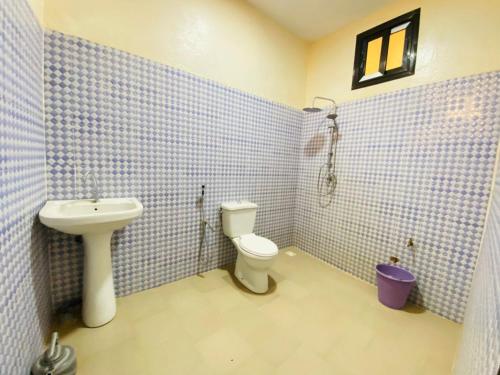 a blue tiled bathroom with a toilet and a sink at Sanga City in Bakel